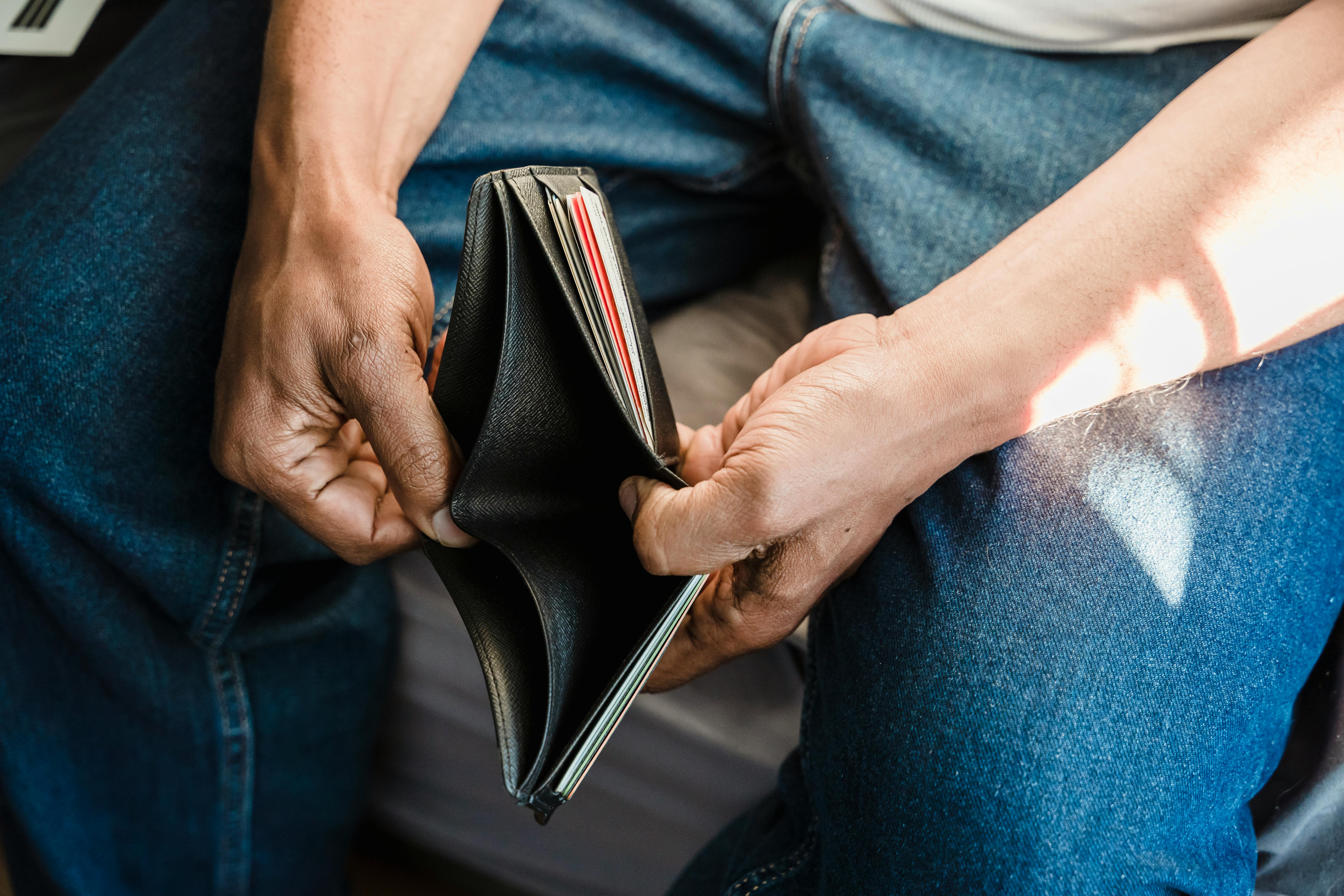 Person holding an empty wallet symbolising financial mismanagement